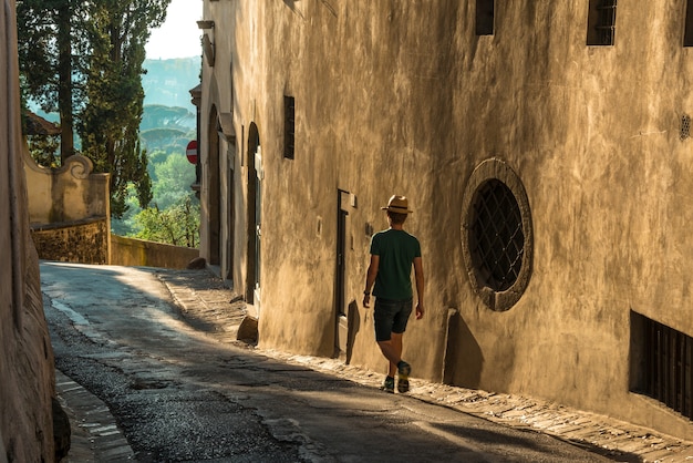 Varón joven solitario caminando por la calle junto a un antiguo edificio de hormigón