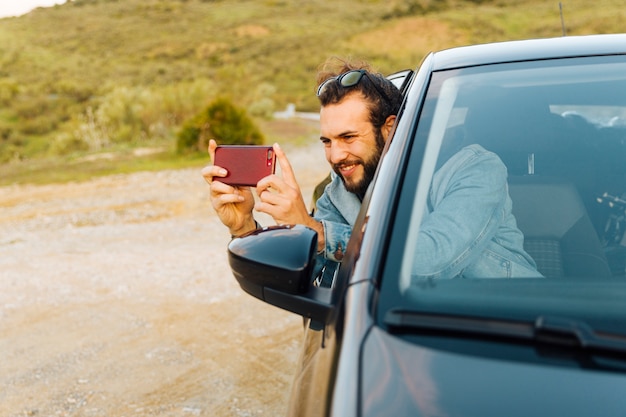 Foto gratuita varón joven sonriente que toma la imagen en el teléfono