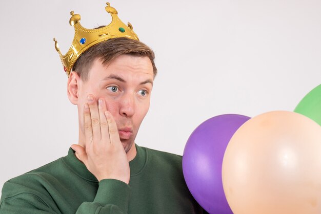 Varón joven sosteniendo globos de colores sobre blanco