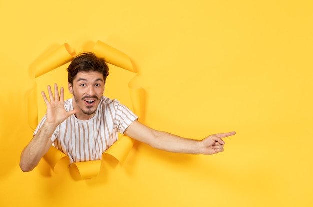 Varón joven en la superficie de papel amarillo rasgado