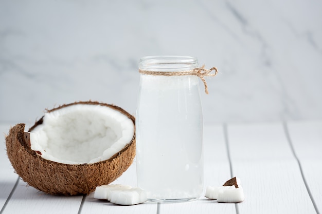 Vaso de agua de coco sobre fondo blanco de madera