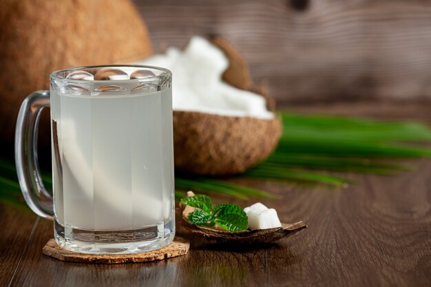 Vaso de agua de coco sobre fondo de madera oscura.