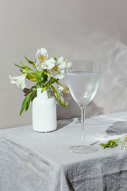 Vaso de agua y flores en la mesa