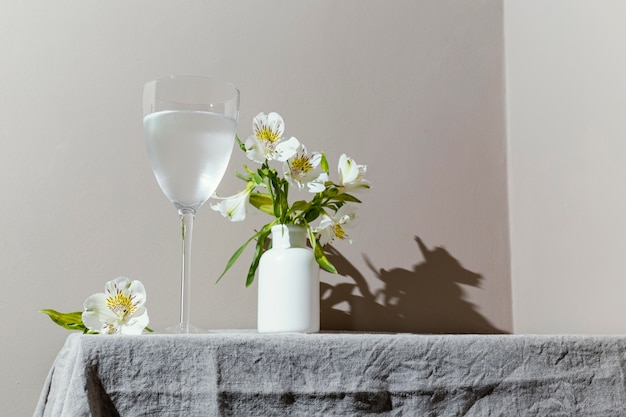 Vaso de agua y flores en la mesa