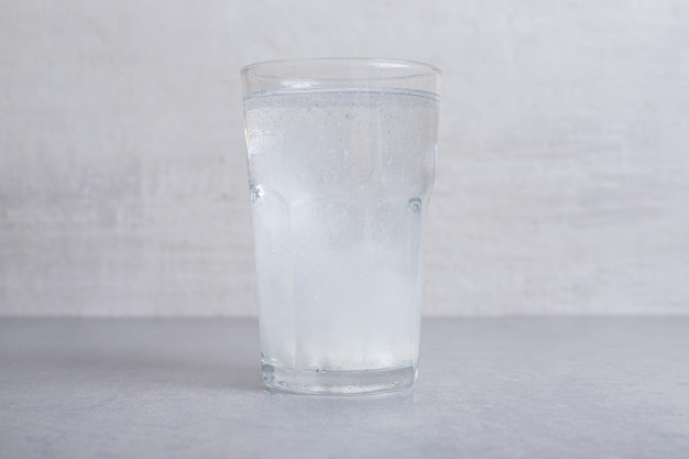 Un vaso de agua fría pura sobre fondo gris.