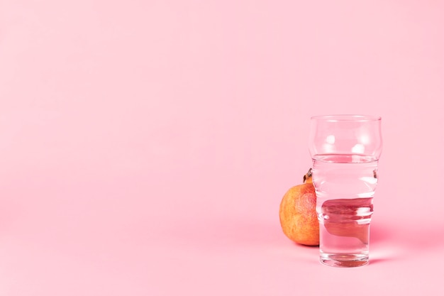 Vaso de agua y fruta de granada