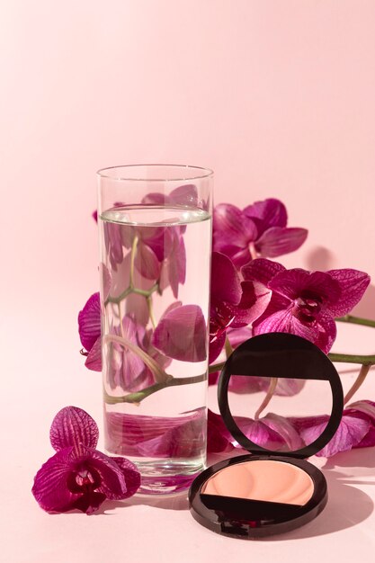 Vaso con agua junto a flores.