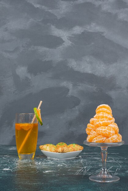 Vaso de agua de limón con plato de panadería dulce y rodajas de mandarina.
