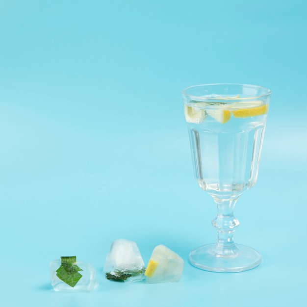 Foto gratuita vaso de agua con limón sobre fondo azul.