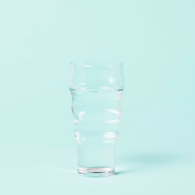 Foto gratuita vaso de agua minimalista sobre fondo azul.