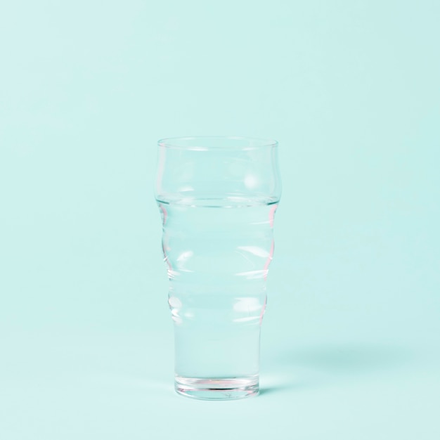 Vaso de agua minimalista sobre fondo azul.