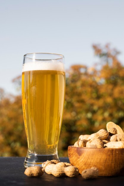 Vaso de ángulo bajo con cerveza al lado del maní