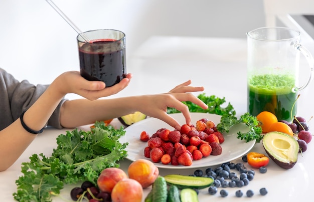 Foto gratuita un vaso de batido de bayas en la mano de un niño en casa en la cocina