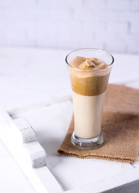 Vaso de batido de caramelo sobre una prenda marrón junto a una superficie blanca