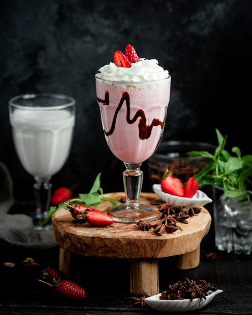 Un vaso de batido de fresa con crema batida y fresa