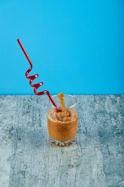 Foto gratuita un vaso de batido fresco con paja sobre mesa gris.