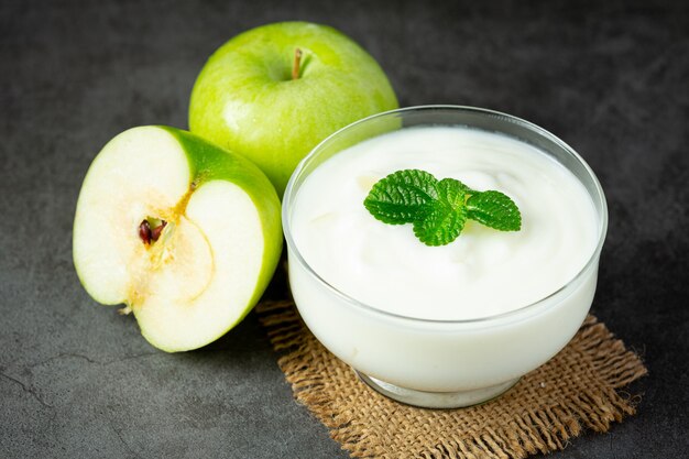 Vaso de batido saludable de manzana verde junto a manzanas verdes frescas