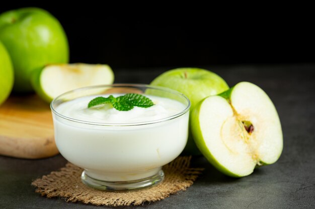 Vaso de batido saludable de manzana verde junto a manzanas verdes frescas