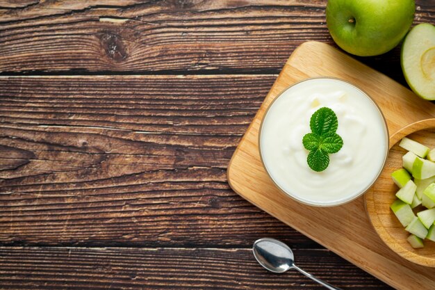 Vaso de batido saludable de manzana verde junto a manzanas verdes frescas