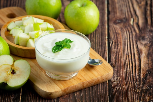 Vaso de batido saludable de manzana verde junto a manzanas verdes frescas