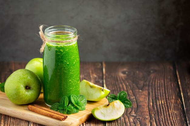 Vaso de batido saludable de manzana verde junto a manzanas verdes frescas