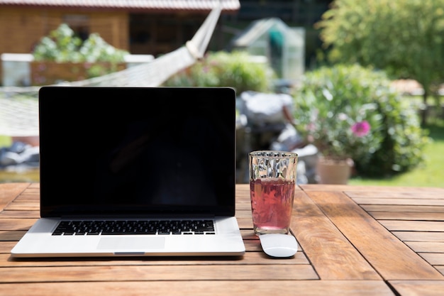 Vaso de bebida cerca de la computadora portátil en el jardín