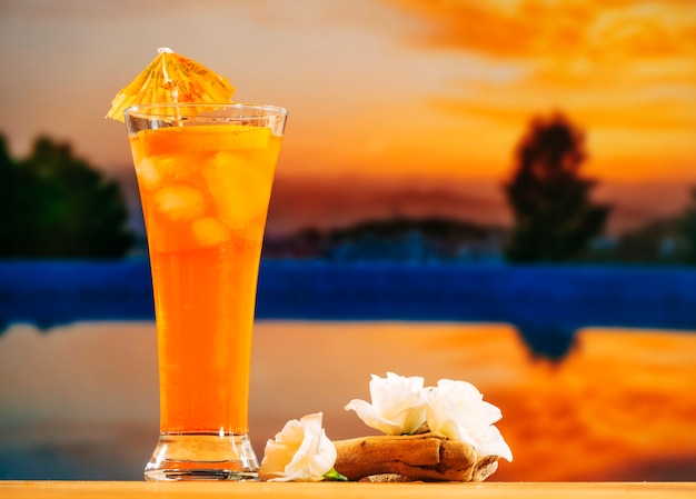 Vaso de bebida de naranja y flores blancas