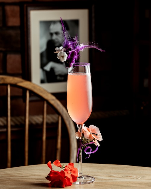 Un vaso de bebida rosa decorada con flores.