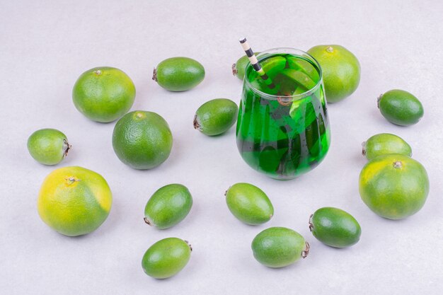 Un vaso de bebida verde con feijoa y mandarinas.