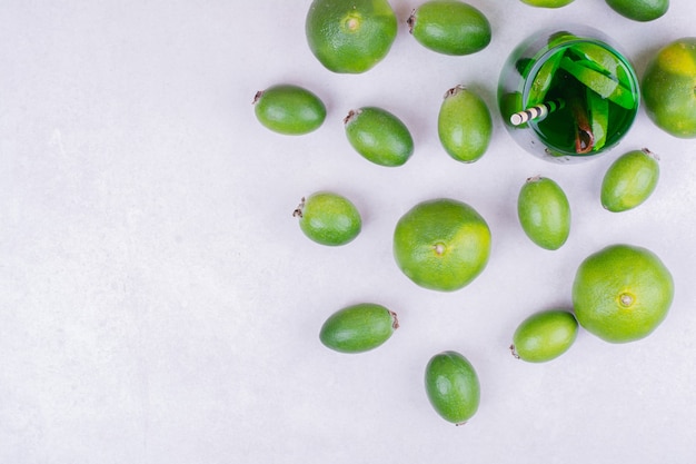 Un vaso de bebida verde con feijoa y mandarinas.