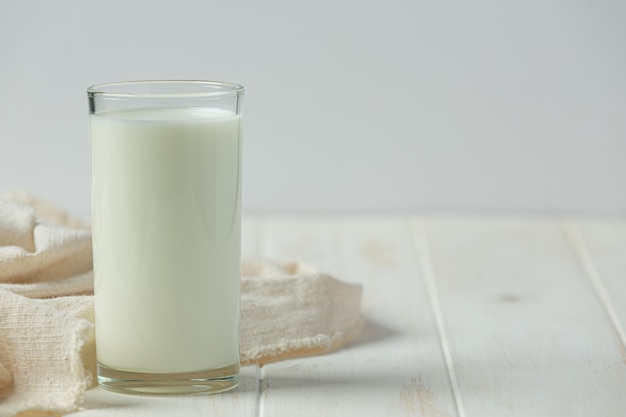 Vaso y botella de leche en la superficie de madera blanca