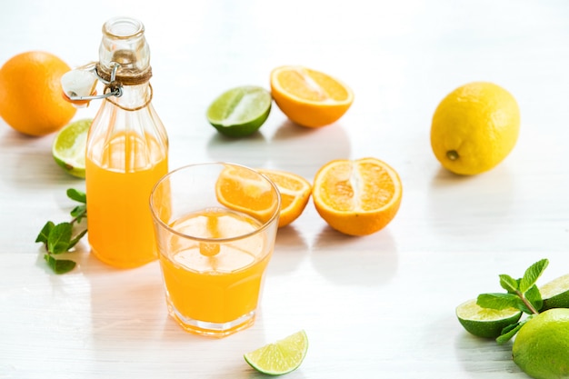 Vaso y botella de licor de naranja y naranjas crudas
