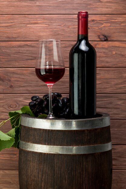Vaso y botella de vino encima de un barril