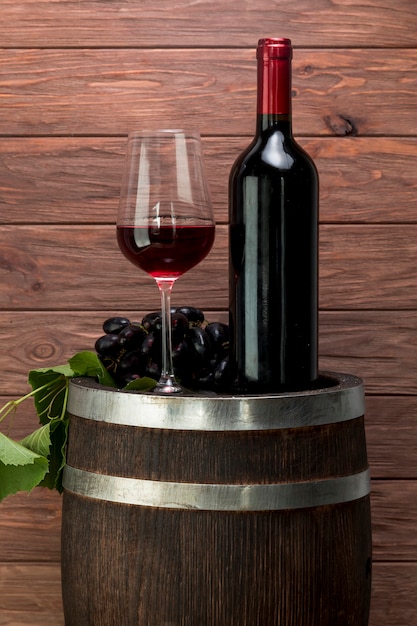 Vaso y botella de vino encima de un barril