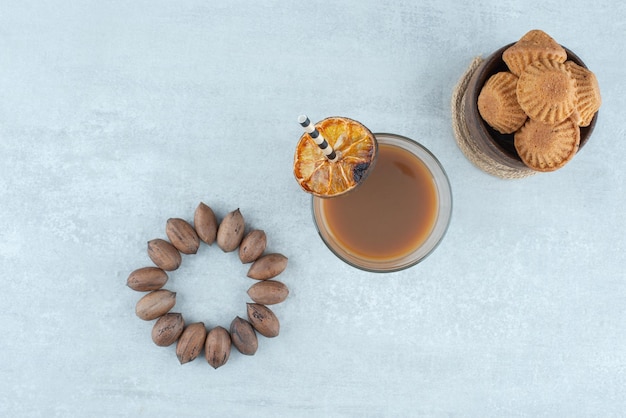 Un vaso de café con nueces y galletas.