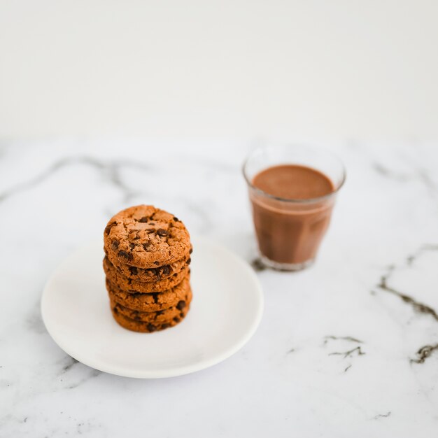 Vaso de café y pila de galletas en la placa sobre el fondo de mármol