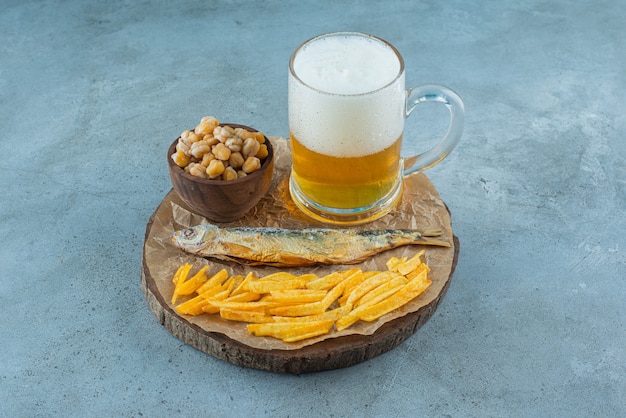 Un vaso de cerveza y aperitivos a bordo, sobre el fondo azul.