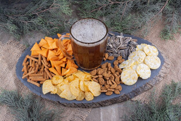 Vaso de cerveza y bocadillos en pieza de madera. Foto de alta calidad