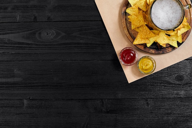 Vaso de cerveza con chips de nachos sobre un fondo de madera.