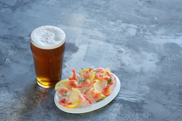 Foto gratuita vaso de cerveza ligera en la pared de piedra blanca. se preparan bebidas alcohólicas frías y camarones con limón para la fiesta de un amigo. concepto de bebidas, diversión, comida, celebración, reunión, oktoberfest.