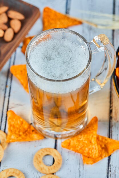 Un vaso de cerveza y patatas fritas en el cuadro azul, de cerca.