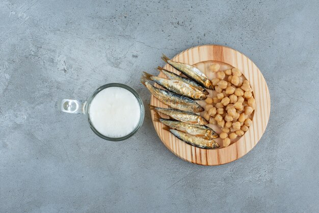 Un vaso de cerveza con plato de madera de pescado y guisantes. Foto de alta calidad