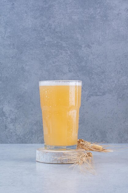 Un vaso de cerveza con trigo sobre superficie blanca