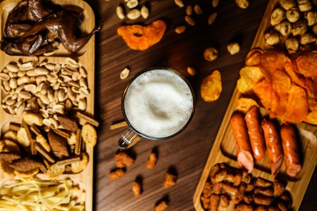 Un vaso de cerveza y varios bocadillos en la mesa para ello.