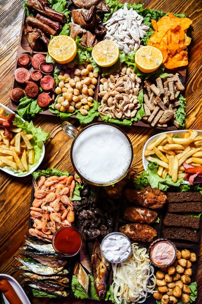 Un vaso de cerveza con varios bocadillos en la mesa.