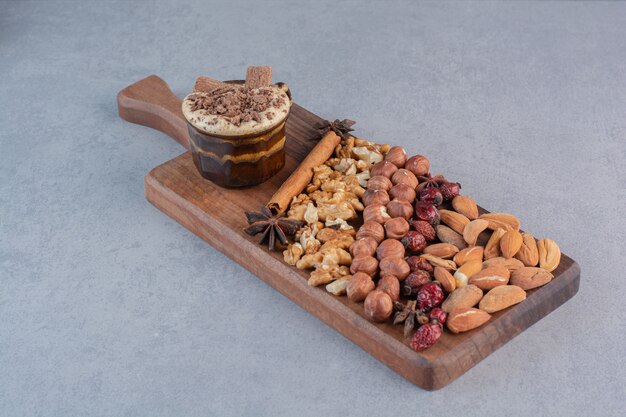 Un vaso de chocolate caliente con un montón de nueces sobre tabla de madera.