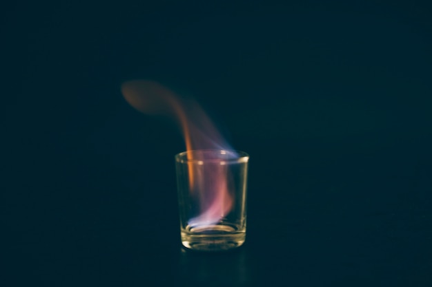 Foto gratuita vaso de chupito de tequila flameante sobre fondo negro