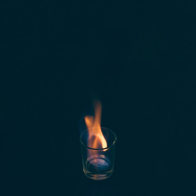 Vaso de chupito de tequila en fuego sobre fondo negro