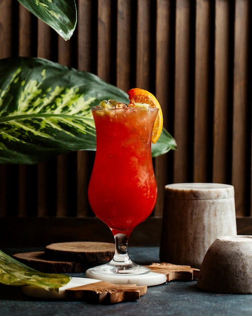 Foto gratuita un vaso de cóctel rojo con hielo y una rodaja de naranja.