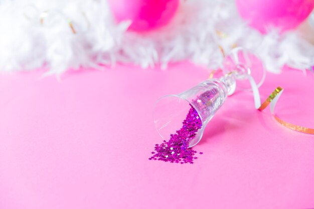 Vaso con confeti cerca de plumas